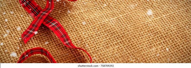 Snow falling against close up red ribbon