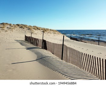 Snow fence on beach with blue sky and dune in background