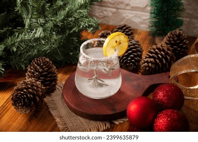 Snow Globe Cocktail. Christmas drink, creative festive beverage in drink glass decorated with rosemary sprig like a christmas pine tree, citrus slice and christmas sparkler. - Powered by Shutterstock