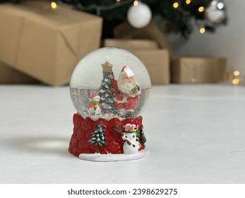 Snow globe with Santa inside, against the background of Christmas decorations - Powered by Shutterstock