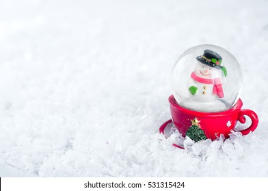 A snow globe with snowman isolated on a white snow background - Powered by Shutterstock