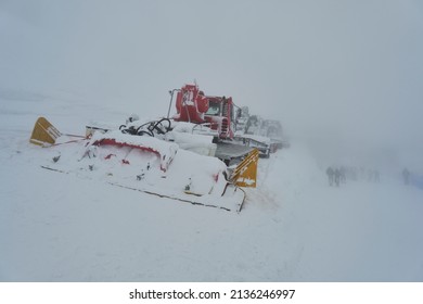 Snow Groomers - Snowcat Ratrack Machines. Machine Preparing Ski Slope Piste Hill At Skiing Winter Resort In Tatra Mountains. In The Background, Blurred Tourists. Snowstorm And Fog.