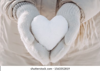 Snow heart in hands. Human hands in warm beige gloves with snowy heart. I love winter or St.Valentine's Day romantic creative concept.