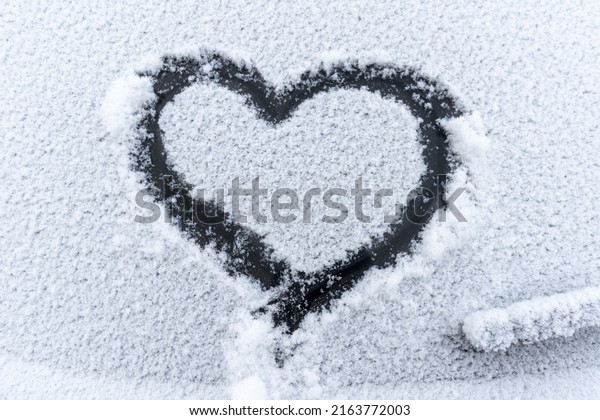 Snow heart\
on the car window with copy space. Heart sign in fresh snowflakes.\
Heart shape symbol drawn on snowed car glass. Love concept.\
Valentine\'s Day. Declaration of\
love