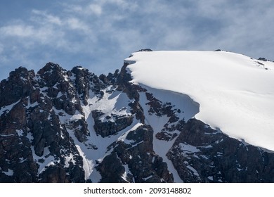 Snow Ledge On The Top Of The Mountain. Ledges From The Snowy Mountains. Cliffs And Large Rocks. Dangerous Terrain.