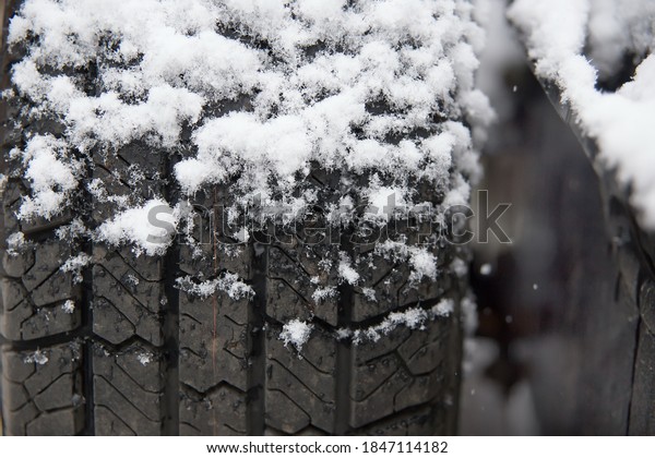 Snow lies on the surface of the car\
wheel. The concept of the need to replace summer car tires with\
winter ones. A photo with a shallow depth of\
field.