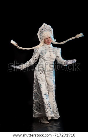 Snow Maiden in a white fur coat, kokoshnik and long hair braids posing on a black background