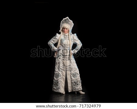 Snow Maiden in a white fur coat, kokoshnik and long hair braids posing on a black background