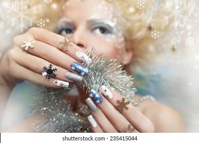 Snow manicure on colored nail Polish with silver snowflakes on the girl.