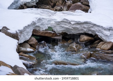 Snow Melting On The Mountains At A Creek With A Snow Bridge