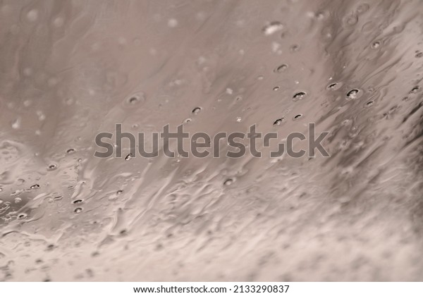 snow melts on glass.\
snowflakes on the glass of a car. raindrops behind glass. window in\
wet snow. bad weather. snowfall. abstract background. snow and\
rain.