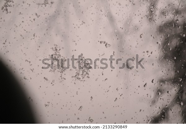 snow melts on glass.\
snowflakes on the glass of a car. raindrops behind glass. window in\
wet snow. bad weather. snowfall. abstract background. snow and\
rain.