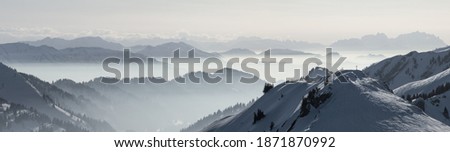 Snow Mountains Panorama in low lying inversion valley fog. Silhouettes of foggy Mountains. Scenic snowy winter landscape. View from Stuiben to Saentis. Alps, Allgau, Bavaria, Germany.