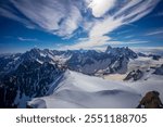 Snow mountains view in the Alps from Aiguille du Midi summit. Rocky mountain peaks scene covered with snow and ice of huge alpine glacier on the massive du Mont Blanc range in Chamonix