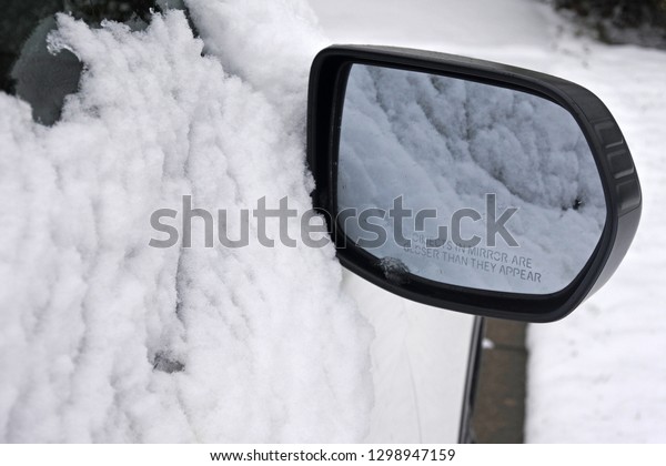 snow on the\
car seen through the rear-view\
mirror