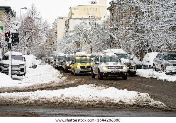 Snow on cars in the morning. Winter season and icy\
cars on the road in morning rush hour traffic of Bucharest,\
Romania, 2020