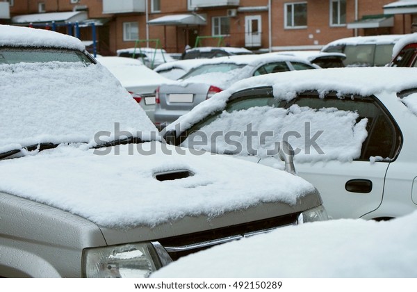 snow\
on the cars parked in the yard near the tower\
blocks