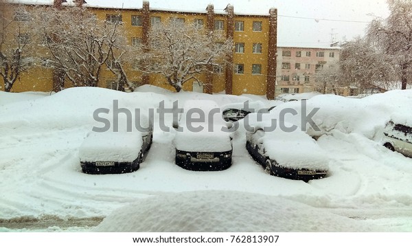 snow on cars and\
road, snow banks in city