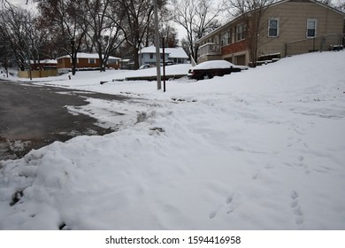 Snow On The Ground And Some Footprints In It. A Neighborhood Of Houses And A Car. Picture Taken In Kansas City, Missouri.