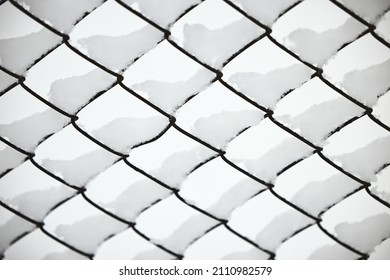 Snow on a mesh fence close-up, snow fence. Abstract winter background. Snow on a wire fence