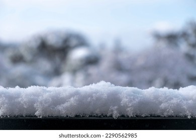 Snow on metal banister on blur nature background. Snowy environment, metallic railing covered with white fluffy snow, cold season, frozen winter day.