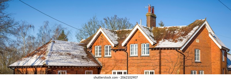 Snow On The Pitched Roof Of A UK Period House In Winter Time, With Wooden Replacement Double Glazing Windows. Panoramic Scene