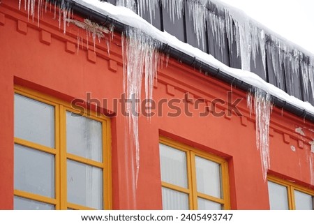 Snow on roof, huge icicles above the entrance. Dangling icicles put pedestrians in danger. Ice dams on residential building. 
