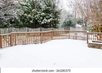 Snow on wood deck and fence with evergreens in background - Powered by Shutterstock