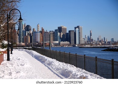 The snow path of the Hudson river walkaway with downtown Manhattan on the back from Paulus Hook in Jersey City - Shutterstock ID 2123923760