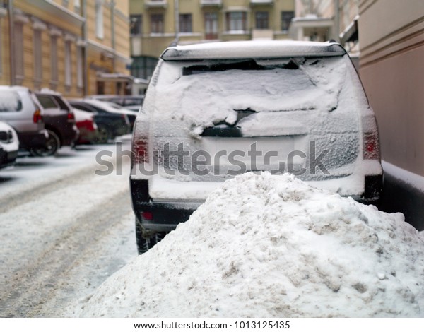 Snow pile and cars parked, concept of winter\
traffic collapse