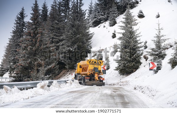 Snow plough truck cleaning a road\
through the mountains after winter massive\
snowfall