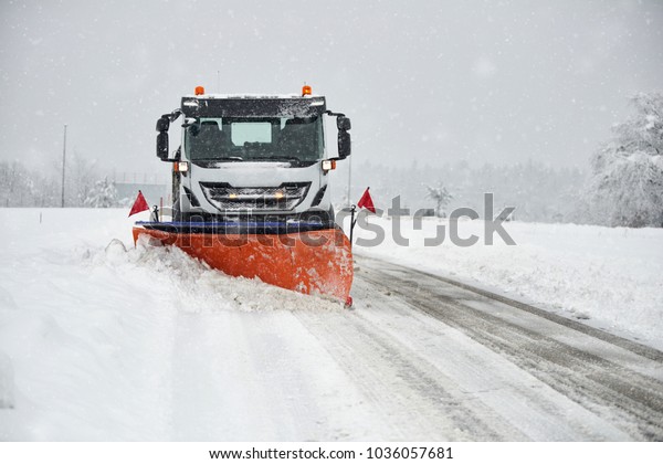 Snow plow clearing a snowy\
road