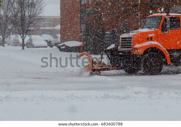 Snow plow\
doing removal after a blizzard in\
suberb.