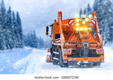 Snow Plow Drive Tackles Snowy Road On Bad Weather And Snow Fall. Snow Plow On Highway Salting Road. Orange Truck Task To Keep Road Clear. 