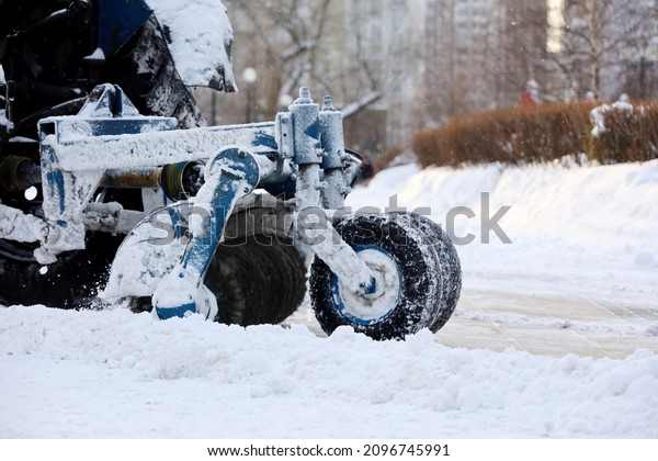 Snow plow machine removing the snow\
on the street. Snowfall in winter city, frost\
weather