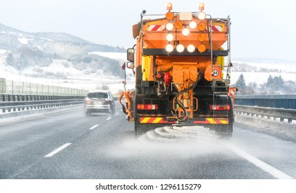 Snow Plow On Highway Salting Road. Orange Truck Deicing Street. Maintenance Winter Gritter Vehicle.