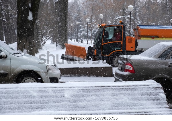 Snow plow is sprincling salt or\
de-icing chemicals on pavement in city. Cleaning service. Frost\
winter season. Winter anti-slip road handling\
concept.