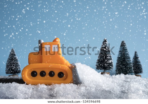 Snow plow. Toy car in a little\
winter landscape. Concept of road cleaning and road\
safety.