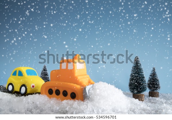Snow plow. Toy car in a little
winter landscape. Concept of road cleaning and road
safety.