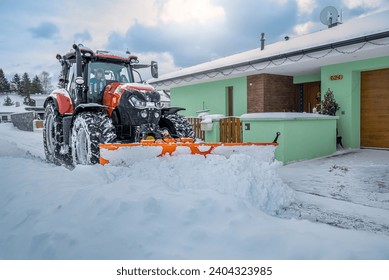 The snow plow tractor while clearing snow on the street.