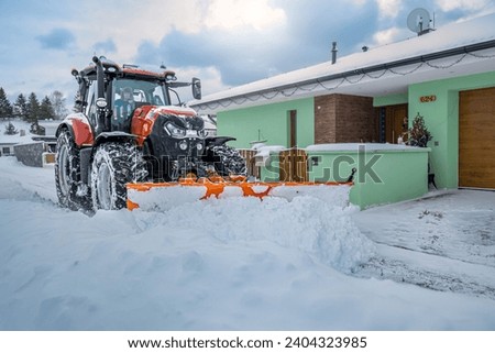 The snow plow tractor while clearing snow on the street.