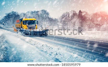 Snow plow truck cleaning snowy road in snowstorm. Snowfall on the driveway.