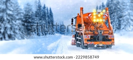 Snow plow truck cleaning snowy road in snowstorm. Snowfall on the driveway.