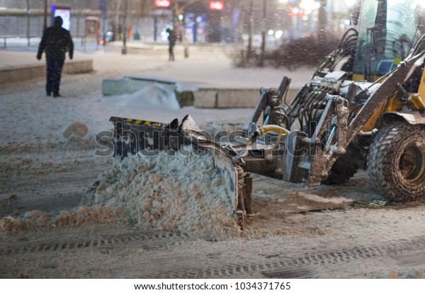 Snow plow\
and snow truck cleaning the streets during a snow storm in night\
maintenance action in Belgrade,\
Serbia