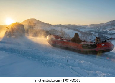 Snow Rafting In Altai Mountains. A Car Drag Uphill A Raft With Tourists. Altai Republic, Siberia, Russia.