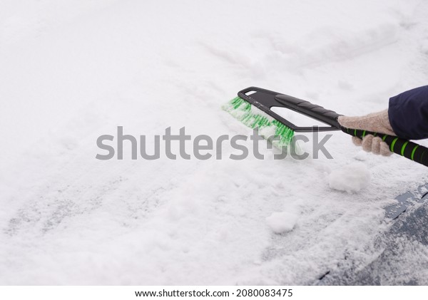 Snow removal, car in snow. Woman cleans the car\
from snow.