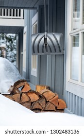 Snow Shovel Hanging Above A Pile Of Firewood At The Front Entrance To A Cabin 