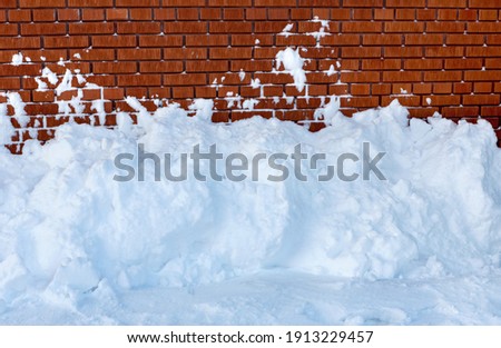 Snow snowdrift against a brick wall. Snow removal.