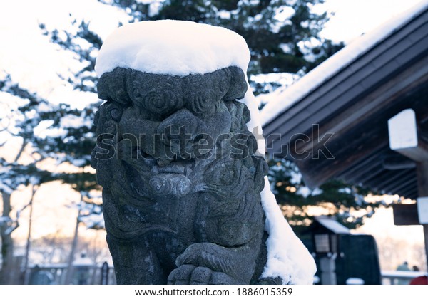 Snow and stone\
lions in a Japanese\
shrine.