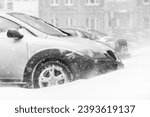 Snow storm, snow-covered street and a car in a snowdrift covered with snow in winter. Blizzard - automobile traffic in bad weather conditions